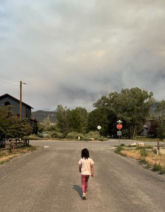 Ava Andrade on a street in Ridgway with a smoke filled horizon Photo by Katey Fetch