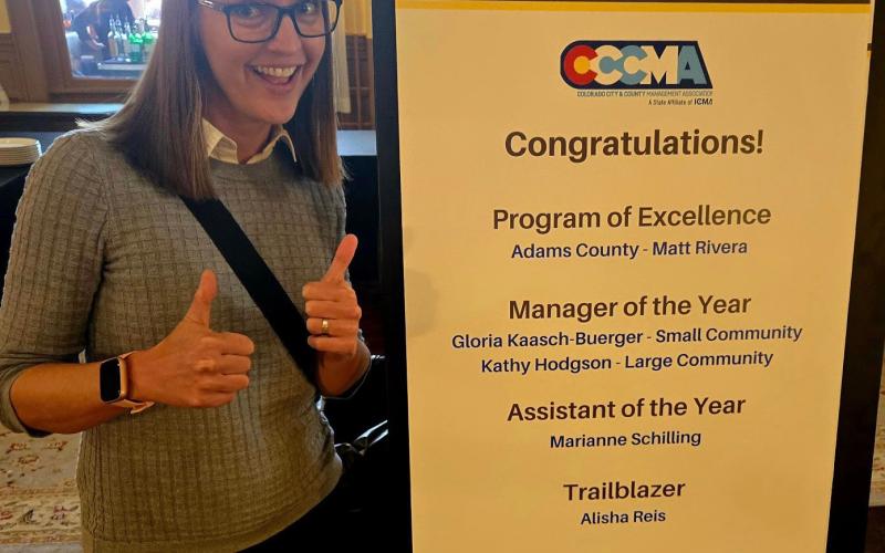 Town Administrator Gloria Kaasch-Buerger poses in front of the CCCMA conference sign that celebrated her big win in Glenwood. Photo credit Gloria Kaasch-Buerger