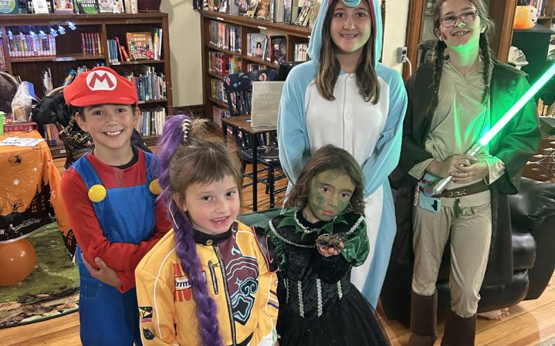 Photo by Misti Anderson Costume contest winner, Ruby Copenhagen, dressed as a K-pop Demon Hunter, surrounded by her pals at the library Halloween party .