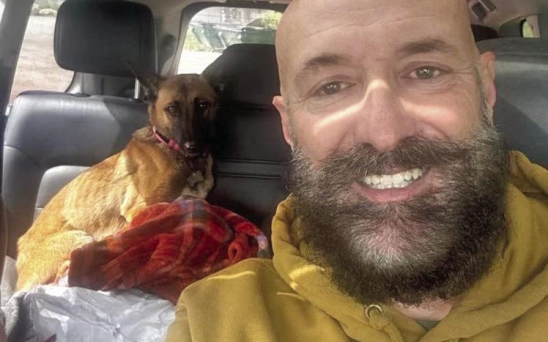 Jimmy Keene smiling with the dog in the back of his car. Photo credit Jimmy Keene