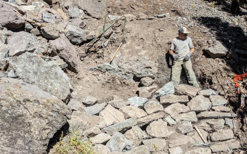 Photo of Tyler Schaffrick building rock walls on trails. The boulders help keep the trails intact &amp; slow down erosion. Photo credit Michael Crockett