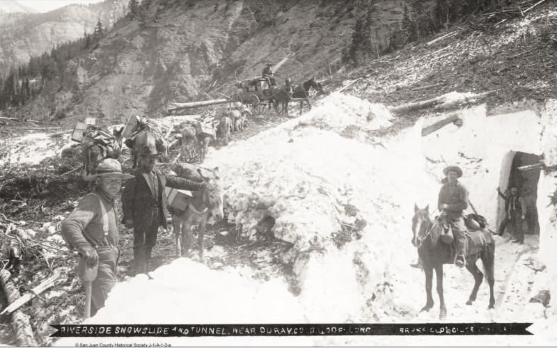 The Riverside Slide on Red Mountain Pass, with a snow tunnel on the right, and horses on top pulling a wagon, along with a pack string of burros to the left in an undated photo.