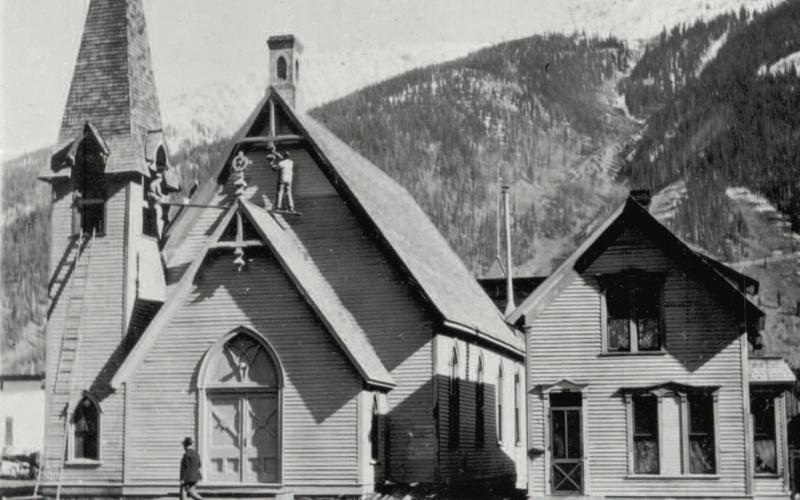 Two men work on the First Congregational Church as a pedestrian strolls by, probably around 1930. Photo courtesy of San Juan County Historical Society