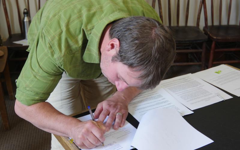 Austin Lashley signing the documents. Photo credit Willy Tookey