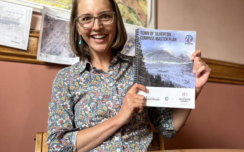 Photo by DeAnne Gallegos Kaasch-Buerger shows off the final Compass Master Plan document after it was adopted.