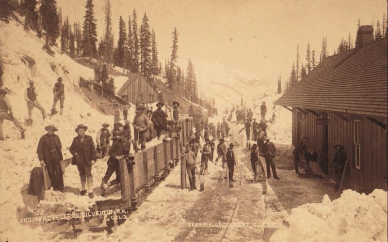 Track shovelers, likely returning from work, at the Red Mountain Town depot. The west face of the depot is at the right, with the main track by the platform and four cars on the western track. Image courtesy of: Judy Stine archives