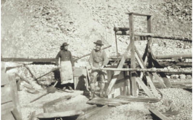 Courtesy of San Juan County Historical Society Two men, with a wheelbarrow working a small headframe device. Date and location unknown.