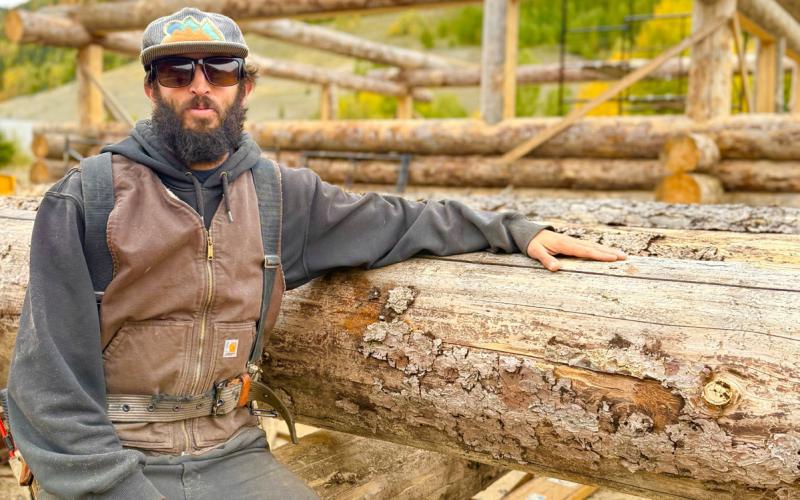 San Juan Structures Ben Roberts working hard moving huge logs around to create his spec cabin. photo by DeAnne Gallegos