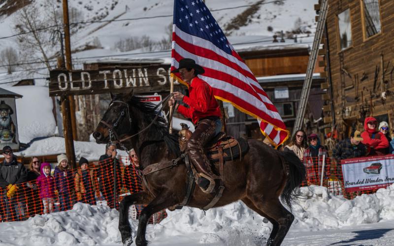 The American flag flies above Richard Weber III of Ridgway on Frank 'n' Beans during skijoring's opening ceremonies in 2024. Photo by Wesley Berg