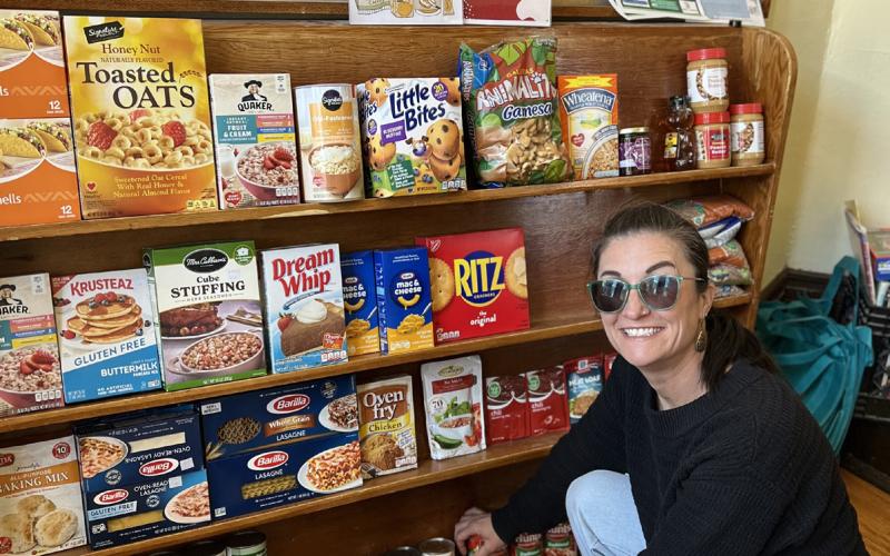 Misti Anderson shows the mini food pantry she has available in the very front of the public library for anyone in need to use at any time when the building is open. Photo credit DeAnne Gallegos