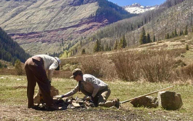 SJMA's Forest Ambassadors Morgan and Kyndall cleaning out a fire ring along South Mineral Road before the crowds arrive for the season. Photo by John Mashburn