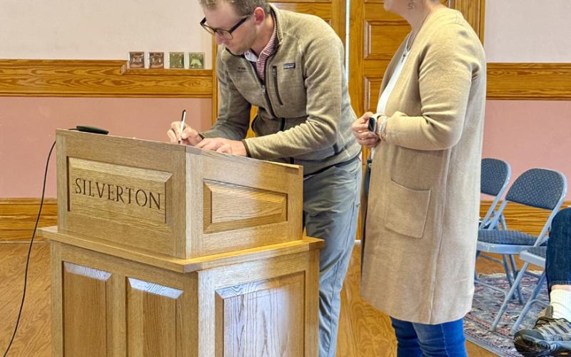 Photo By DeAnne Gallegos Town of Silverton Trustee Christopher Brosh signs his Oath of Office in front of San Juan County Judge Kelly Tompkins