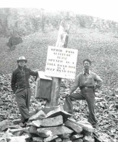 William McGuire Sr. and his Son William Maguire Jr. standing beside the stenciled Ophir Pass sign and registry box atop the pass in 1954, a year after it opened to Jeep traffic.