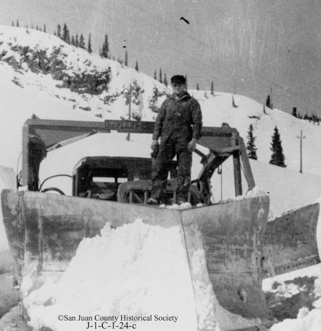 Red Mountain Pass, 1932 A 21-foot A-shaped wedge plow on U.S. 550 on Red Mountain Pass, with Louie Dalla standing on the blade.