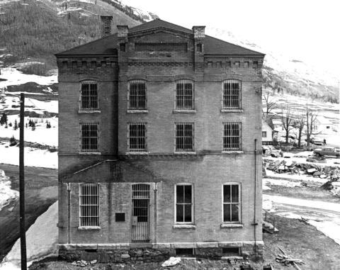Fifteen years after opening as a museum, the 1902 jail suffered a major setback when the heavy snows of the 1978- 79 winter collapsed the roof of the building, forcing temporary museum relocation itoa house on Greene Street while repairs were made. This 1981 picture shows the new roof on what appears to be a neglected building. The facing porch on the southwest side had been destroyed in an unfortunate collision with a motor vehicle.
