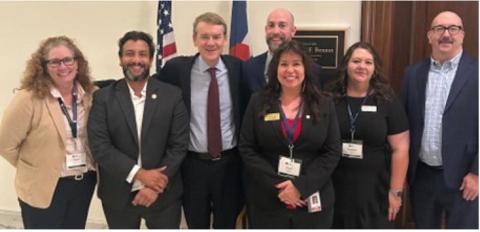 Senator Michael Bennet pictured center of flags and Charles Alex Lanis to his right meet with fellow Colroado Election Officals
