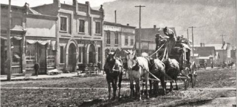 A stagecoach approaches the Hotel Imperial from lower Greene Street. This would have been a coach making regular trips between Silverton and Ouray. The view shows a street ditch and wooden sidewalks in front of the hotel, a hanging streetlamp, and business buildings in the 1100 block of Greene Street, east side, in the background. Photo courtesy of the San Juan County Historical Society