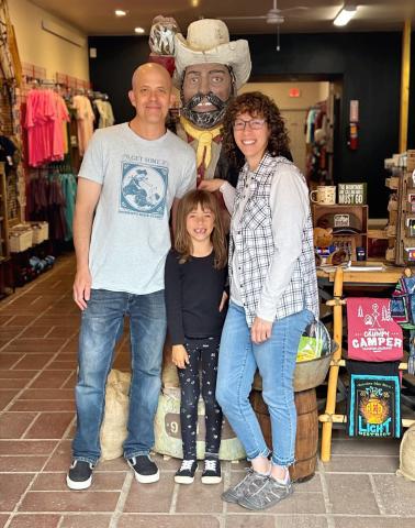 Wyatt Carmack, Anyela Carmack, and Gina Rosato pose with the old miner inside the new Timberline Trading. Photo credit Gina Rosato
