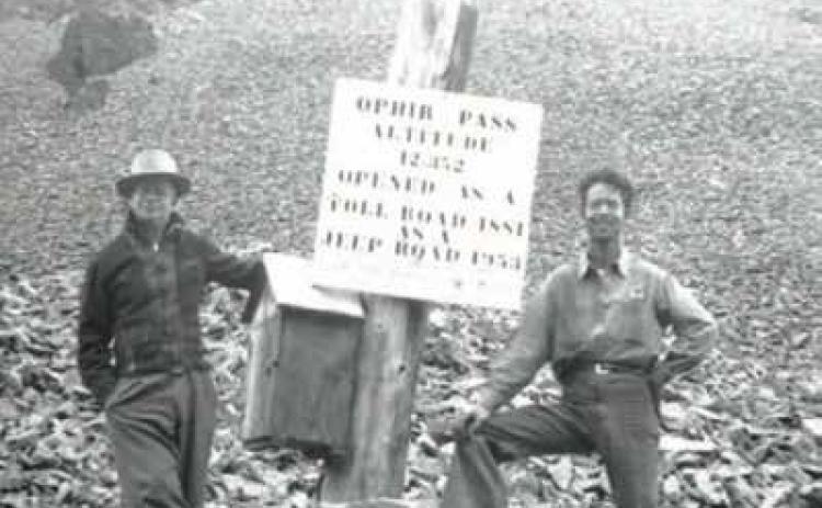 William McGuire Sr. and his Son William Maguire Jr. standing beside the stenciled Ophir Pass sign and registry box atop the pass in 1954, a year after it opened to Jeep traffic.