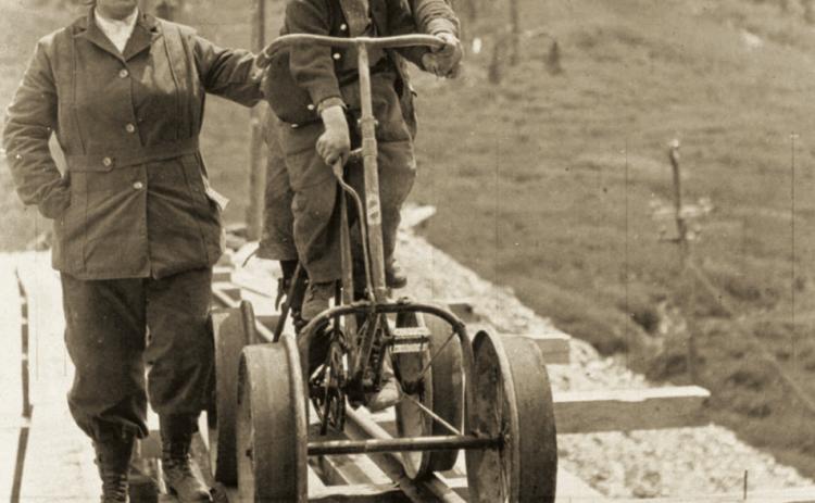 A mine bicycle on mine rail in August 1914 at the Frisco Tunnel near Animas Forks. From left are Mrs. Henson, Fred Henson and Dan McNaughton Jr.