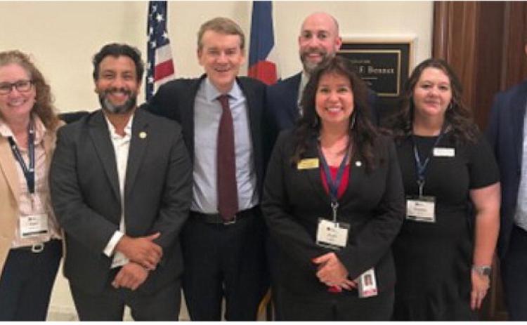 Senator Michael Bennet pictured center of flags and Charles Alex Lanis to his right meet with fellow Colroado Election Officals