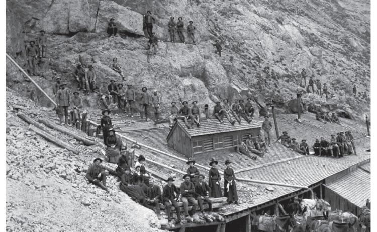 Photo of horseback trip taken by group called the Silverton Walking Club, to the mines on King Solomon Mountain. Party posed with miners and workmen at the North Star - King Solomon Mine above timberline. Several saddled horses in the foreground, including a white one with a man standing amid the horses. Women are posed with the workmen - they are on the left side of the photo. San Juan County Historical Society photo