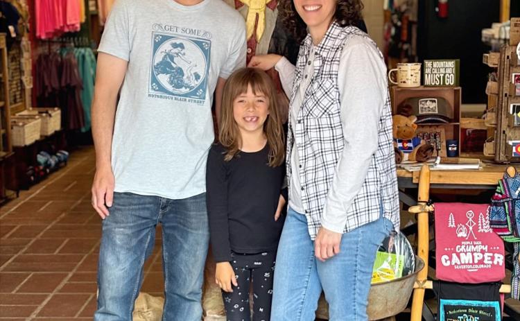 Wyatt Carmack, Anyela Carmack, and Gina Rosato pose with the old miner inside the new Timberline Trading. Photo credit Gina Rosato