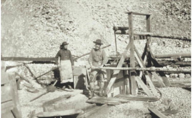 Courtesy of San Juan County Historical Society Two men, with a wheelbarrow working a small headframe device. Date and location unknown.