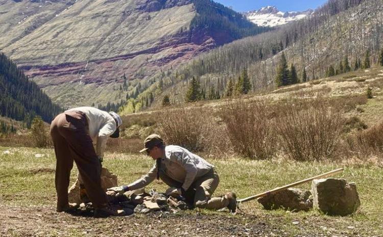 SJMA's Forest Ambassadors Morgan and Kyndall cleaning out a fire ring along South Mineral Road before the crowds arrive for the season. Photo by John Mashburn