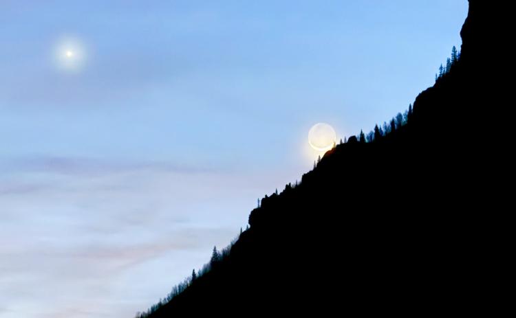 The crescent moon coming out of a new moon this week, peaking over Anvil mountain with a bright star nearby photo by DeAnne Gallegos